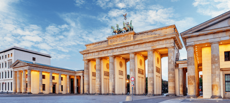 Dawn breaks over Berlin's iconic Brandenburg Gate, casting a warm glow over the neoclassical monument that stands as a testament to Germany's rich history, juxtaposed with its modern role as a nuanced destination for cryptocurrency taxation and investment