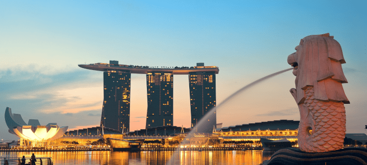 Singapore's iconic Marina Bay Sands Hotel and ArtScience Museum bask in the warm glow of sunset, with the Merlion fountain statue proudly in the foreground, symbolizing the city-state's progressive and favorable tax policies for cryptocurrency investors and traders